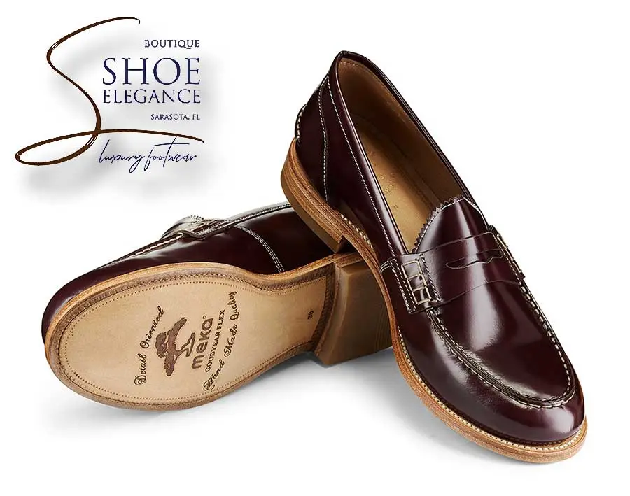 A pair of men's handmade reddish-brown leather penny loafers with a Goodyear welted sole and contrast stitching.