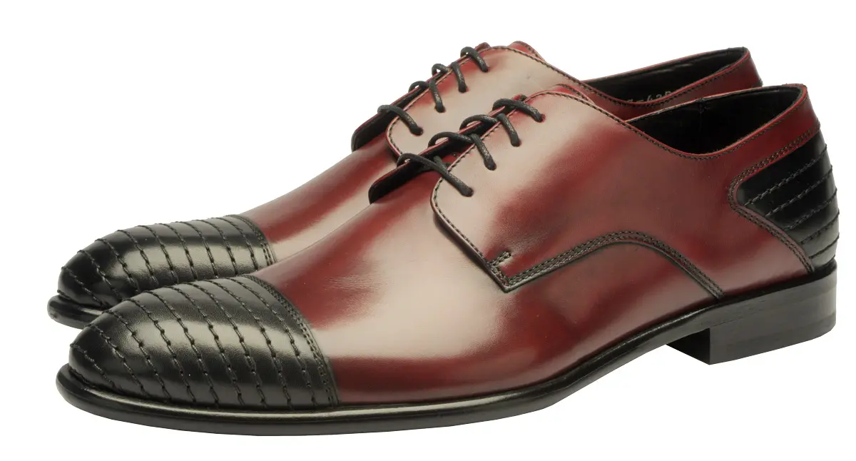 A pair of men's two-tone leather oxford shoes. The main body is a polished reddish-brown, while the cap-toe and heel counter are black with a basketweave texture.